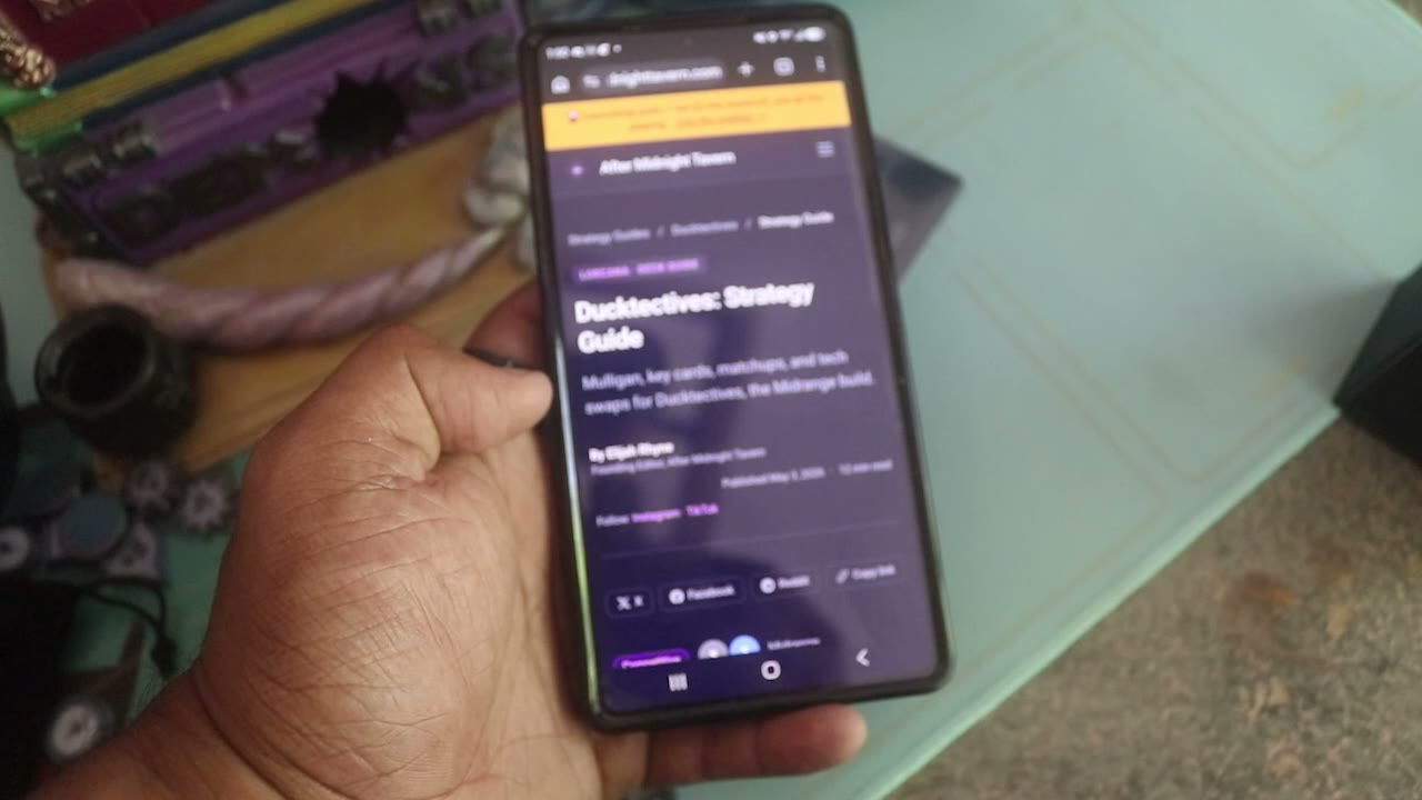A Ducktectives strategy guide open on a phone, scrolling through key cards and how to play